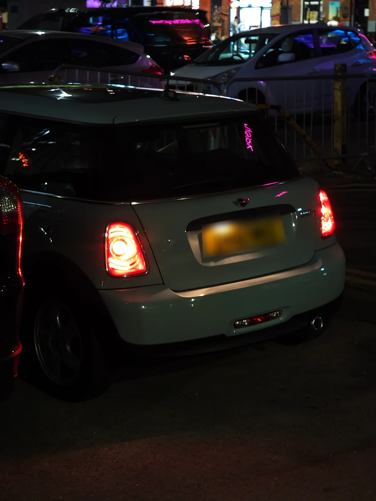 Cream MINI R56 in city traffic at night
