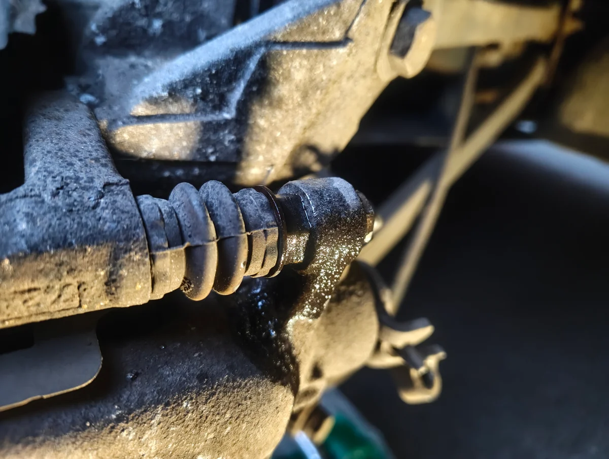 Spraying penetrant on the top brake caliper slider pin fixing bolt.