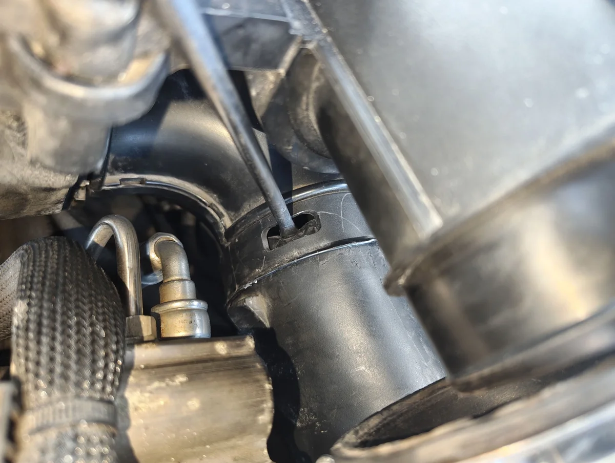 Pressing left side air intake clip in with a flathead screwdriver