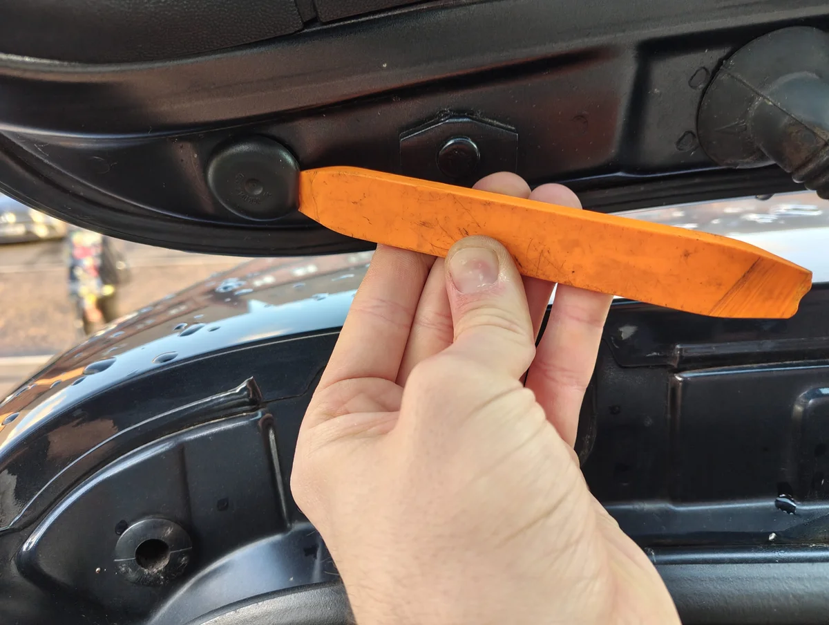 Prying rubber cap off with plastic pry bar