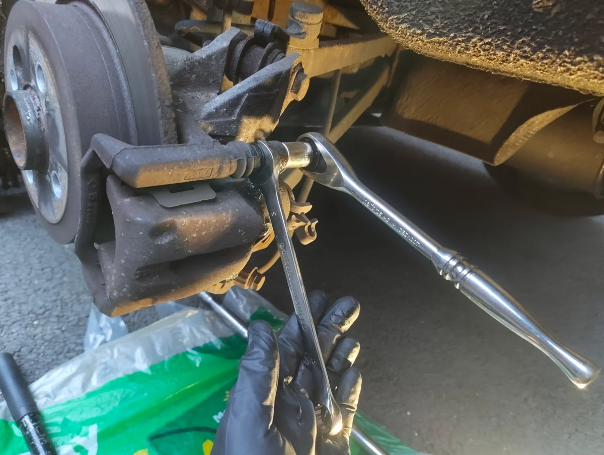 Ratchet and spanner on brake caliper top bolt