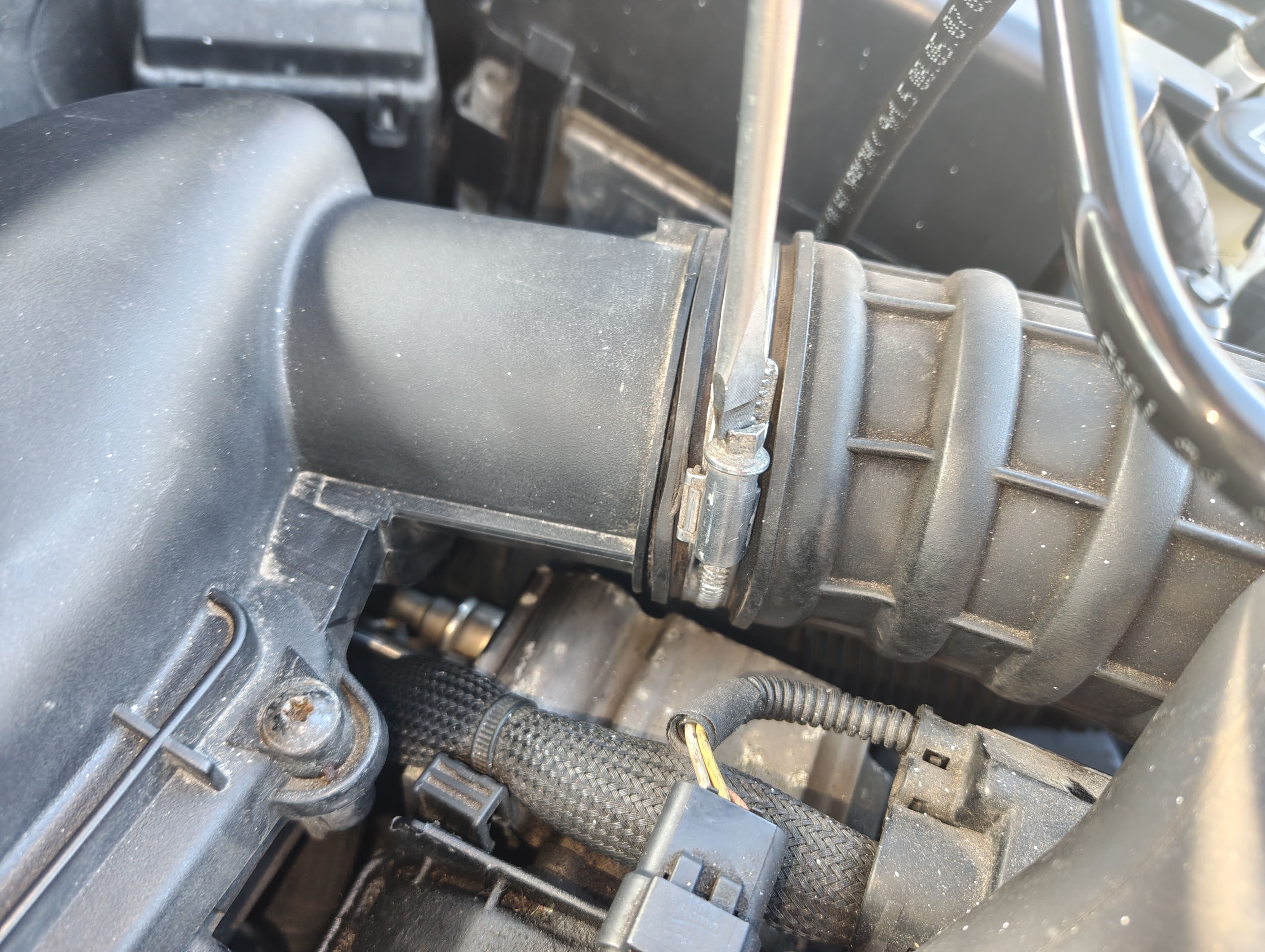 Unscrewing intercooler pipe band clamp connected to the air filter housing