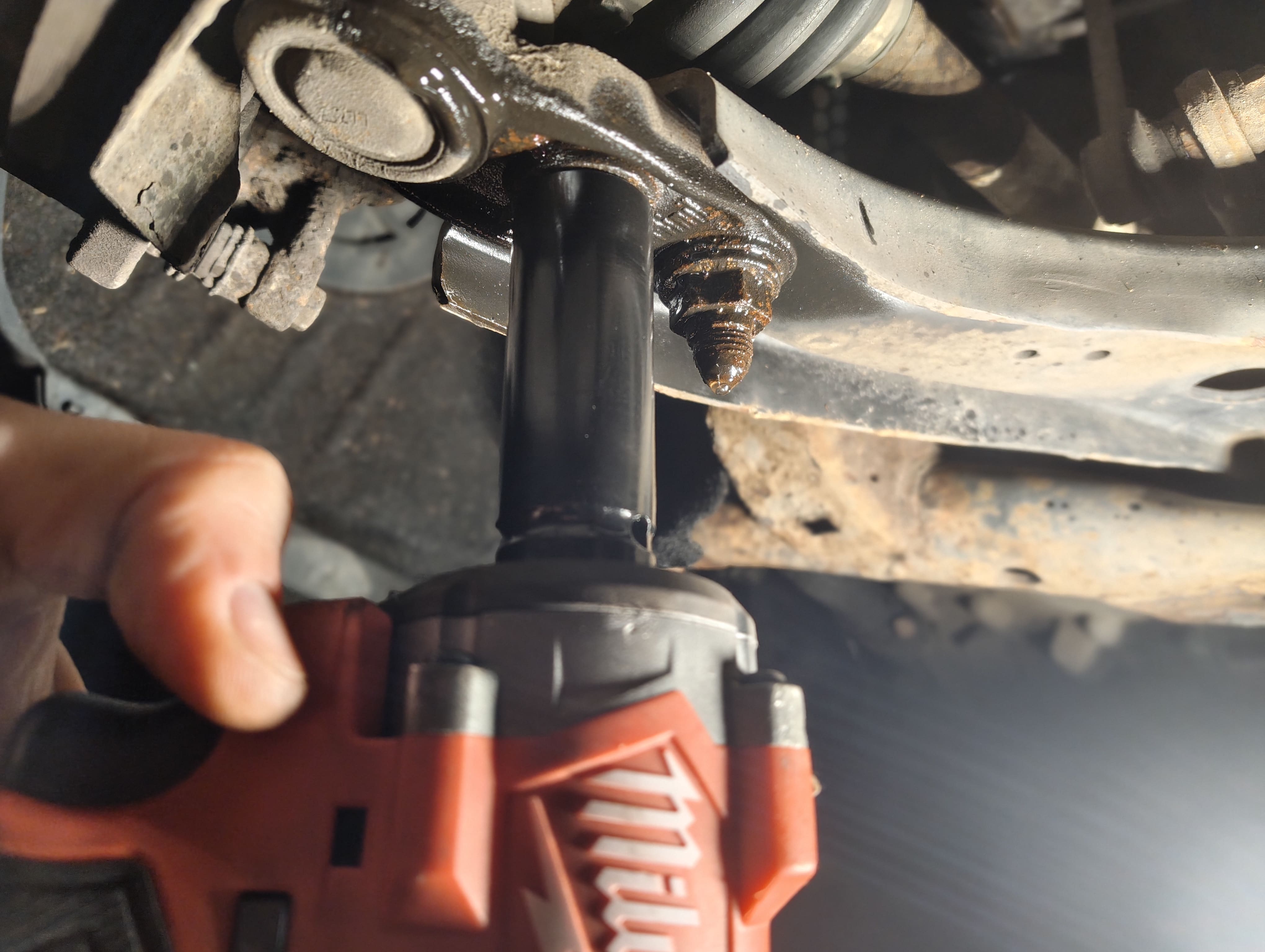 Removing the front passenger-side lower ball joint nuts with an impact wrench